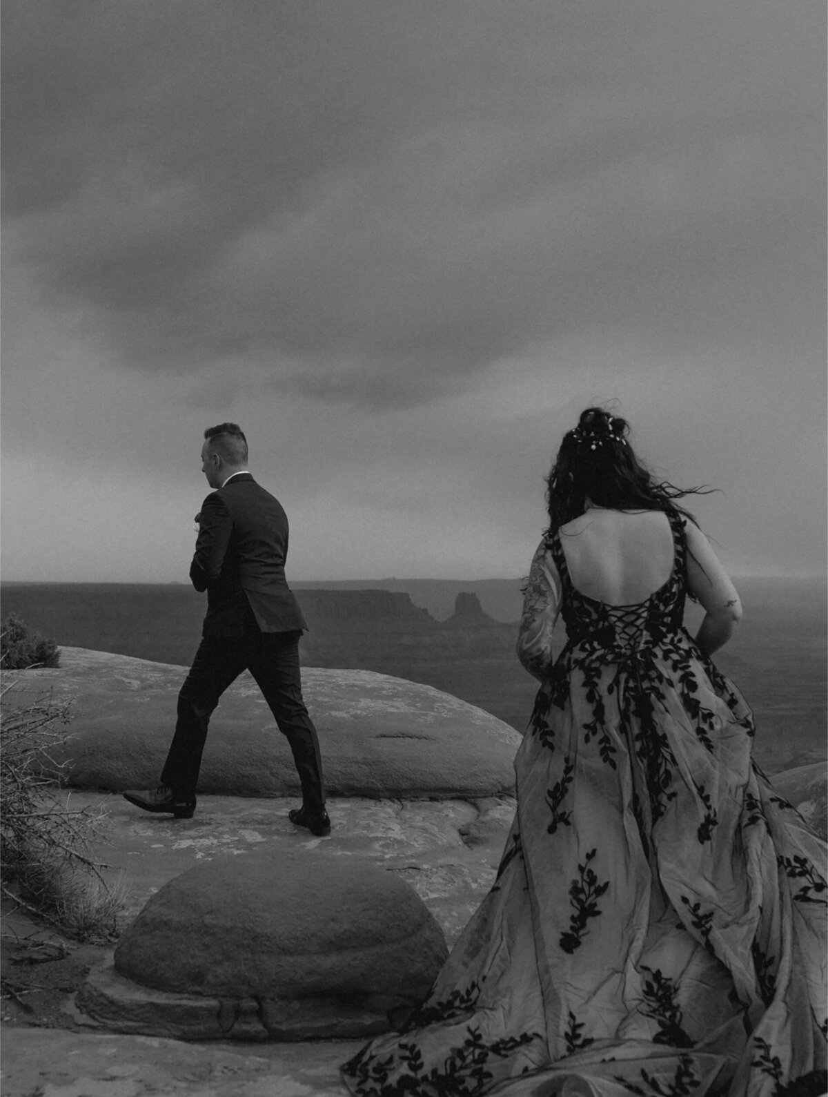 private elopement couple walking along cliffside in Moab, Utah