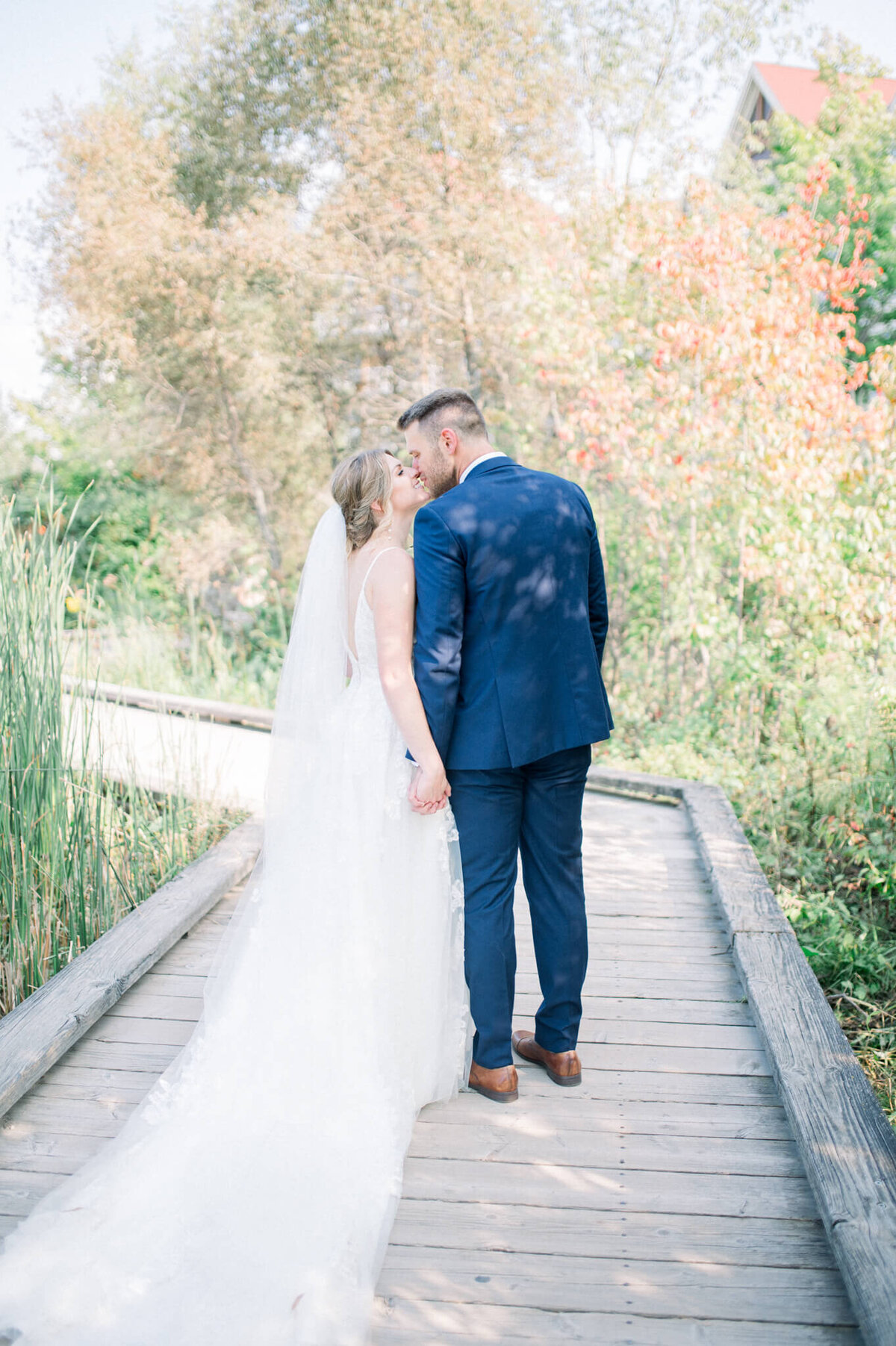 Niagara wedding photography of bride and groom kissing on a bridge pathway