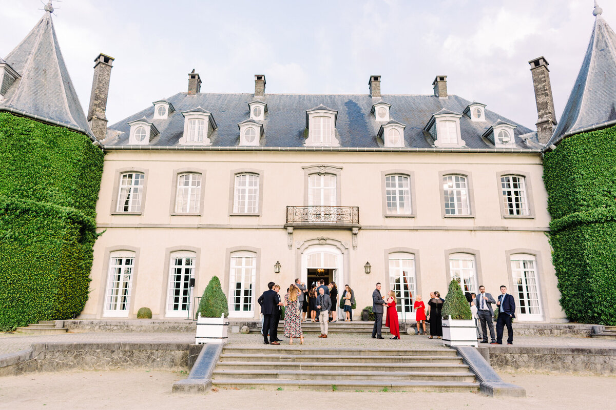 A wide-angle view of a romantic château wedding reception, glowing under the evening sky.