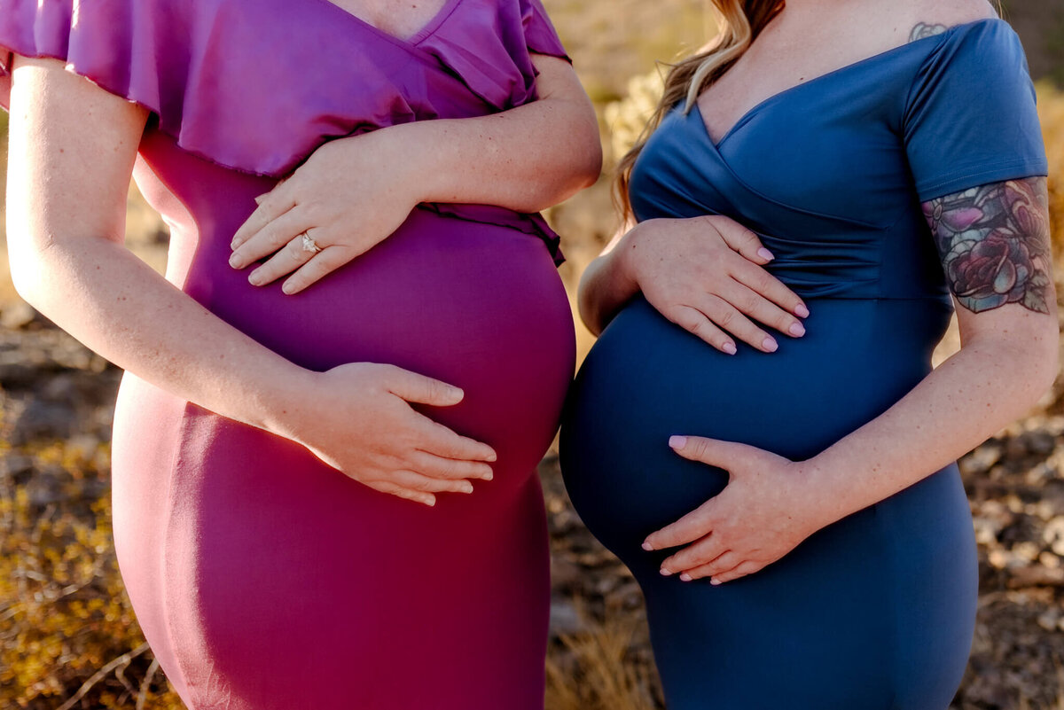 two mothers side by side for a close up of their similar maternity bumps
