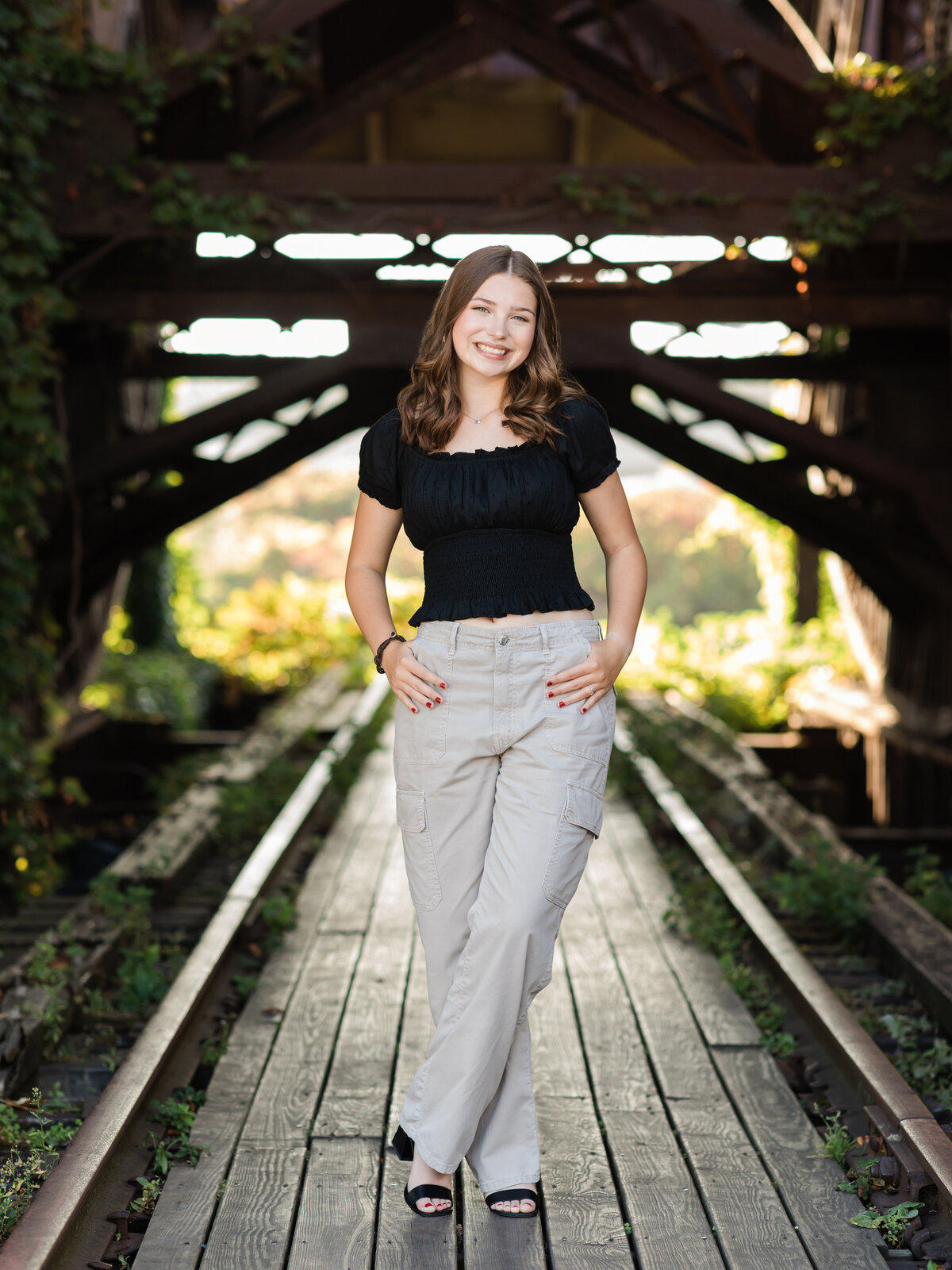 senior girl in black shirt posed at shooters on the water for senior portraits 