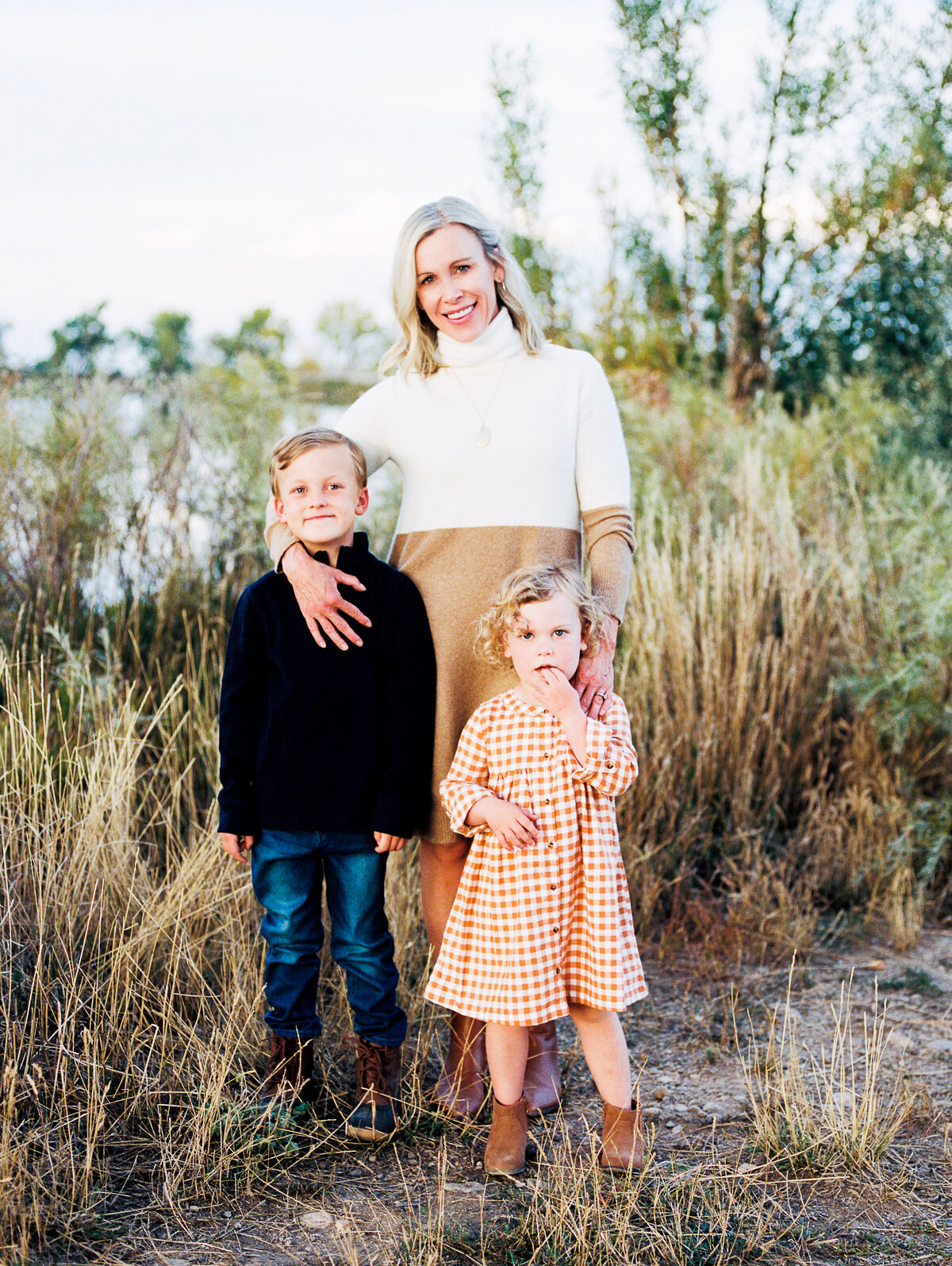 son and daughter stand in front of mom during outdoor photography session
