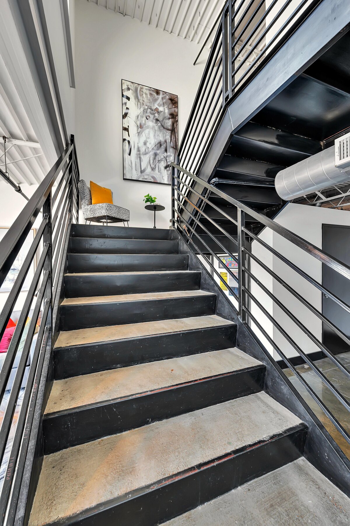 Staircase leading to the bedroom in this top floor two-story industrial condo in the historic Behrens building with skyline views, fully stocked kitchen and room for 6 in downtown Waco, TX.