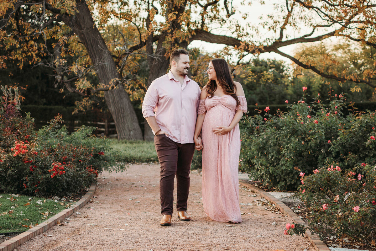 Mom and daD walking through roses during a maternity photo session in Wheaton IL