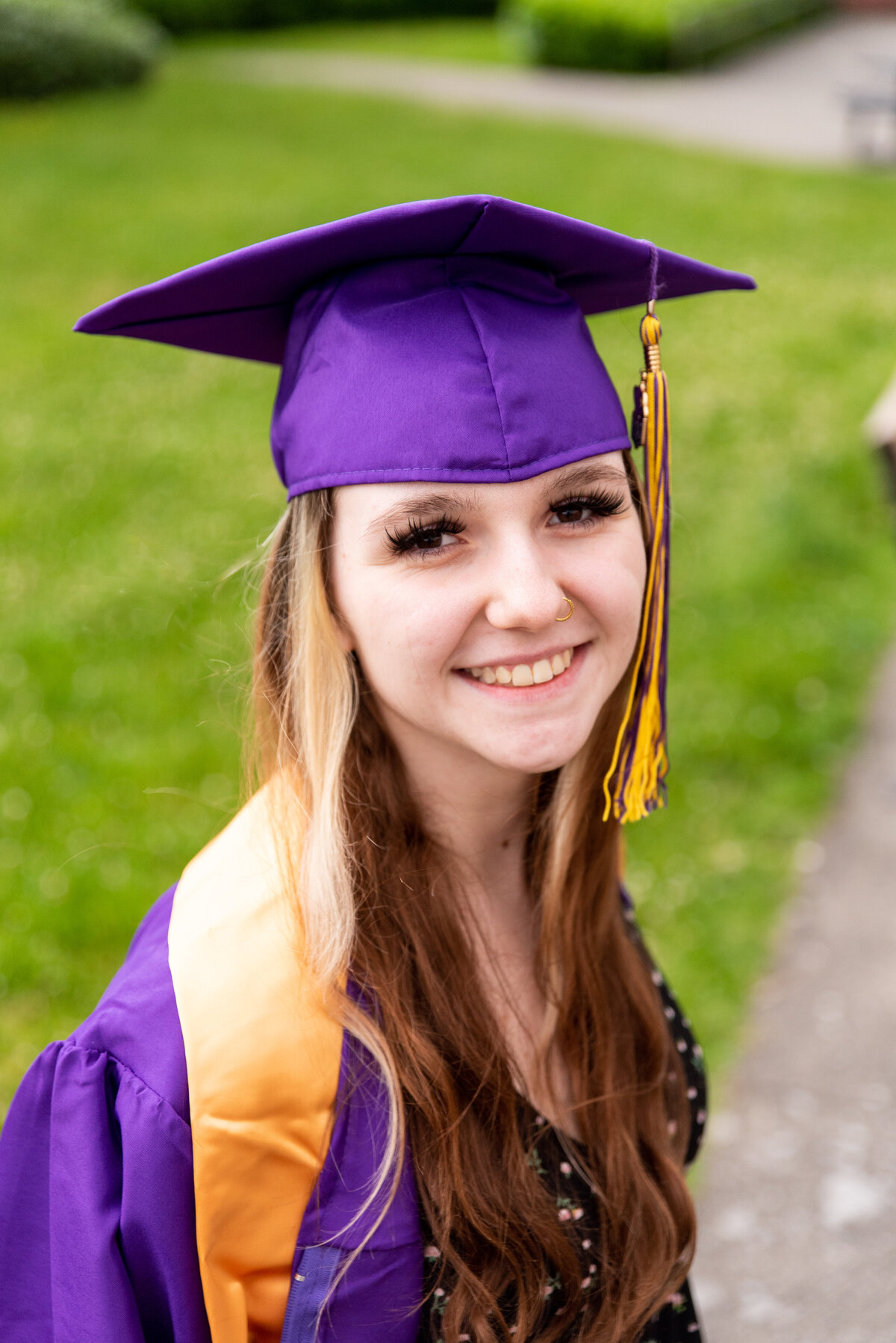 Girl sitting on a bench in her cap and gown for senior portaits