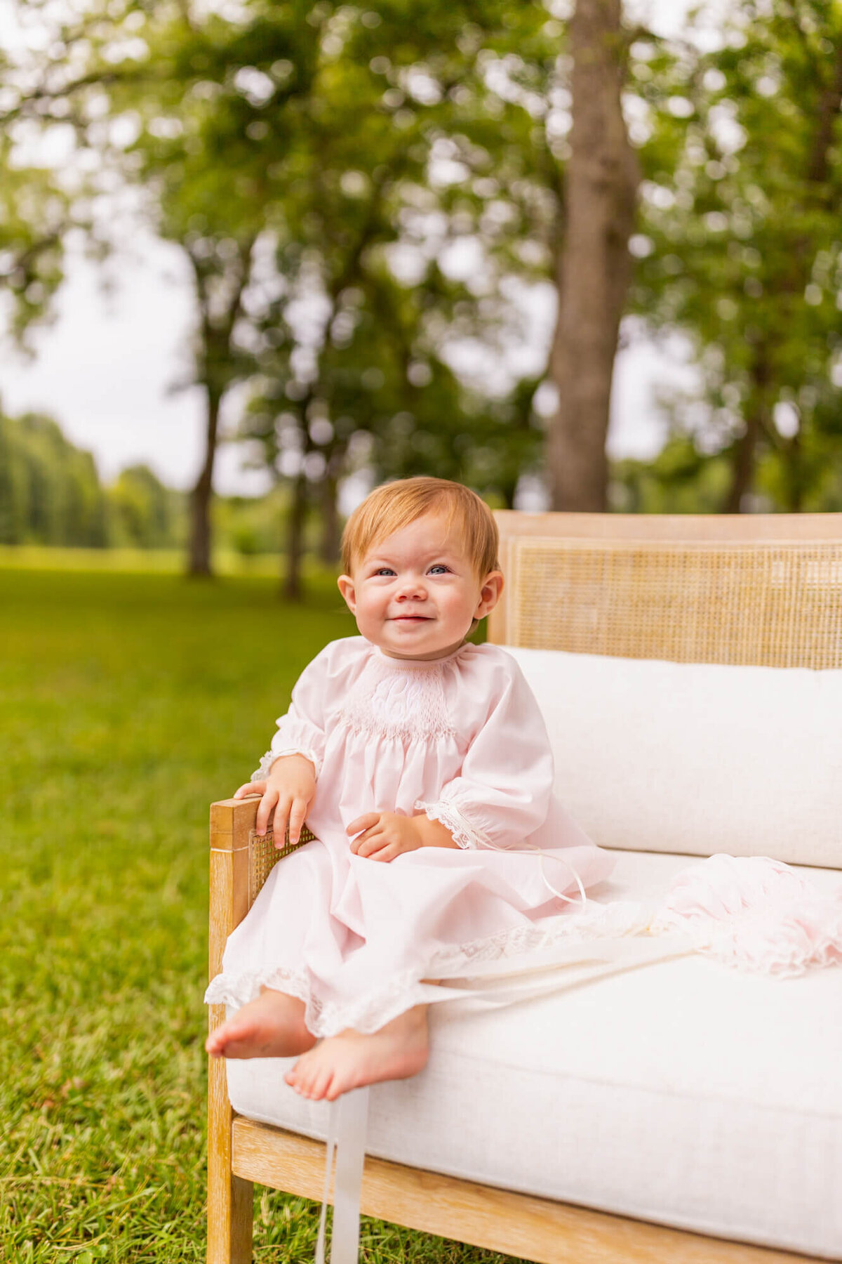 toddler girl sitting in a chair in a field wearing a pink dress