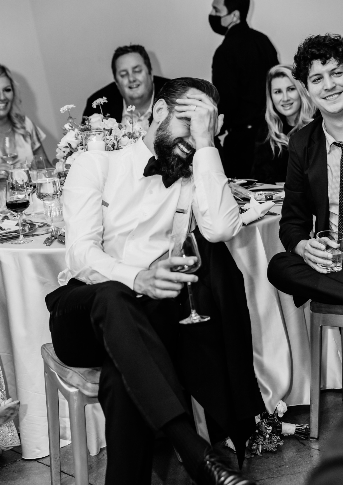 Man holding his face in his hands laughing at wedding reception