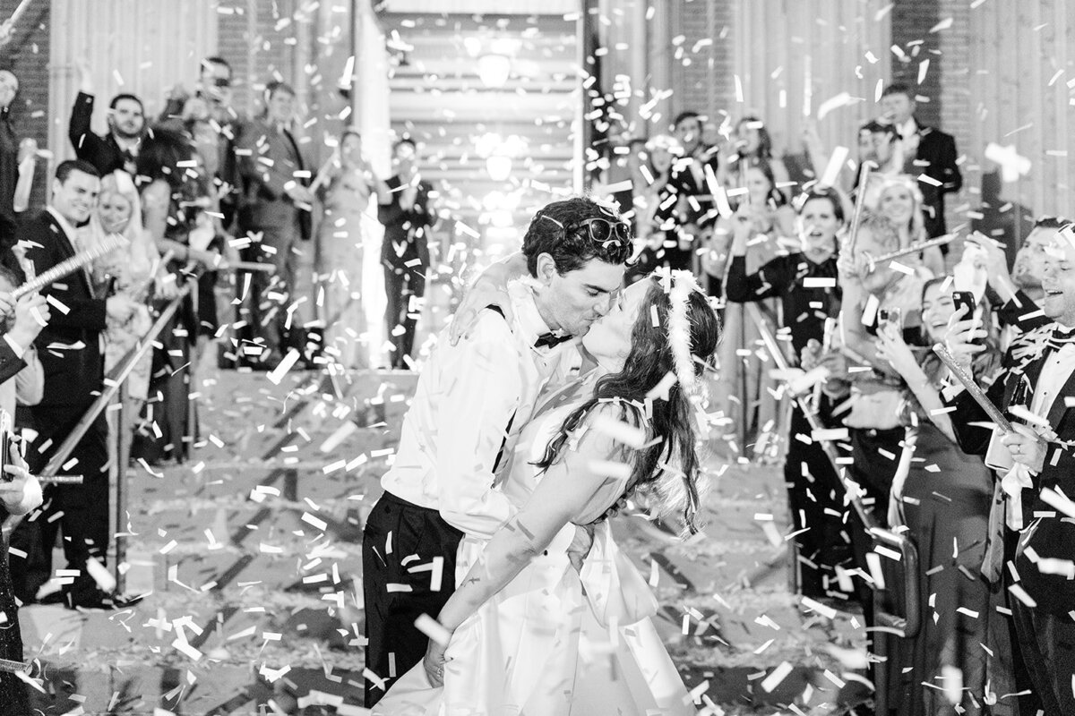 Bride and groom kissing at confetti exit from reception