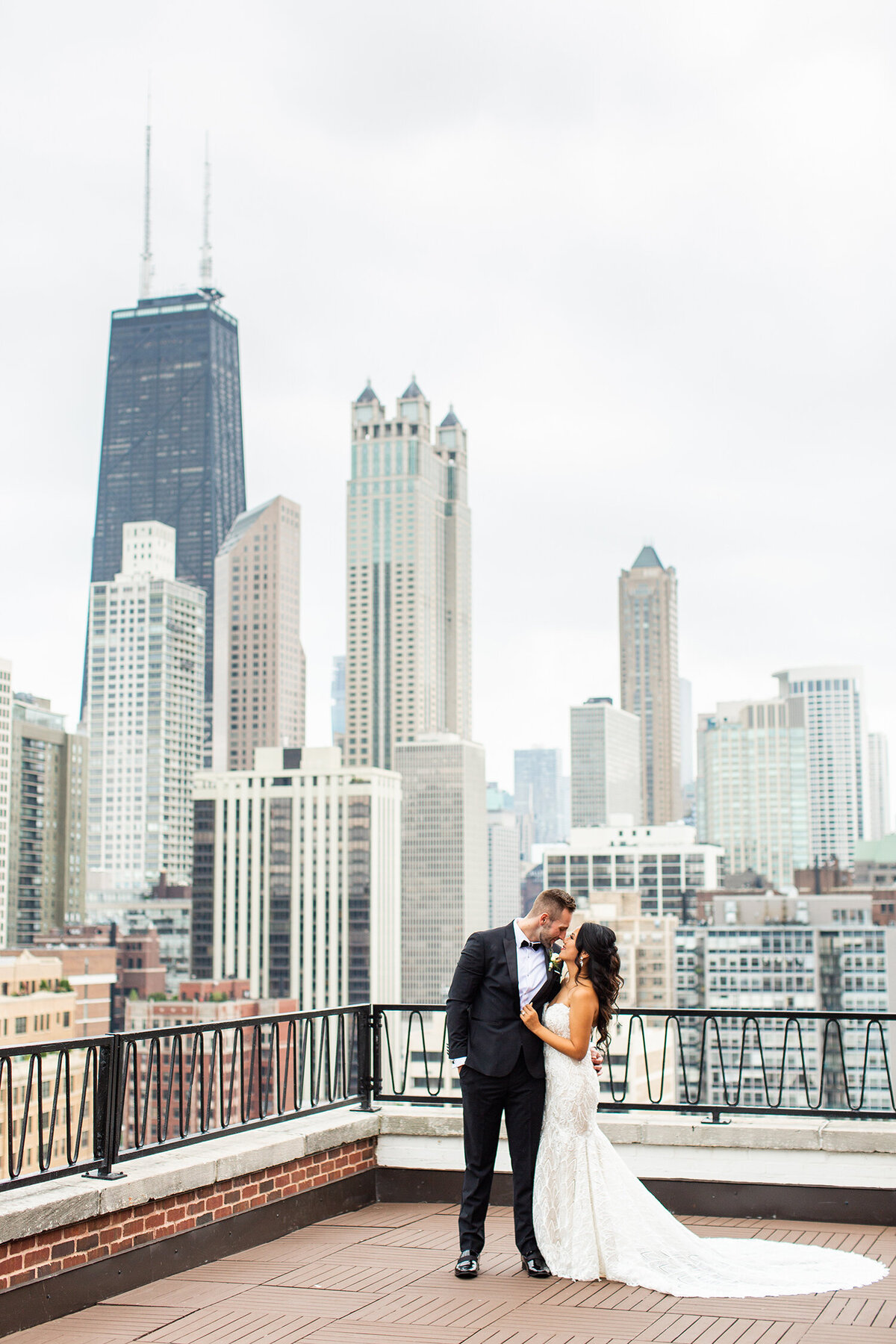 Bride and groom embracing on a rooftop with a city skyline in the background