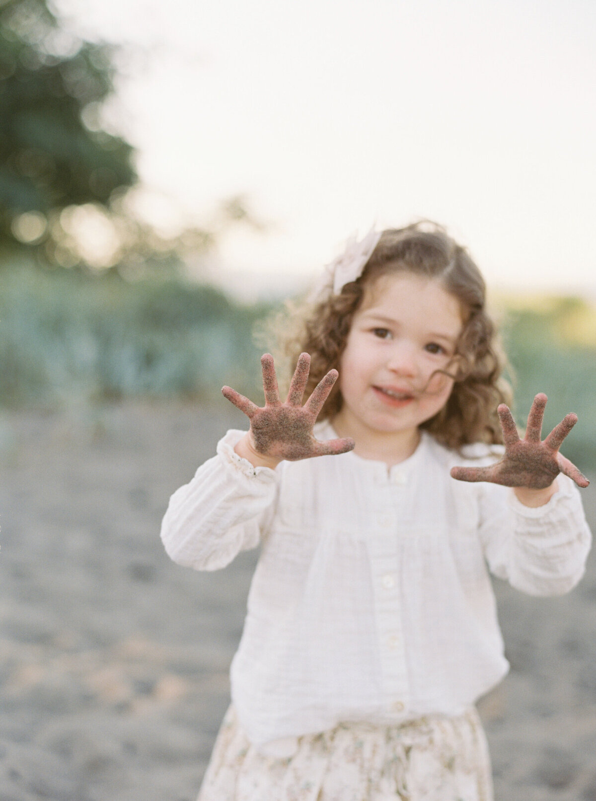 little toddler with sand on her hands at the beach