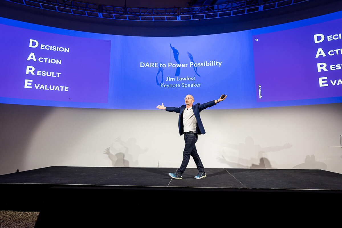 Professional headshot style of keynote presenter walking confidently across large stage during business conference new jersey.