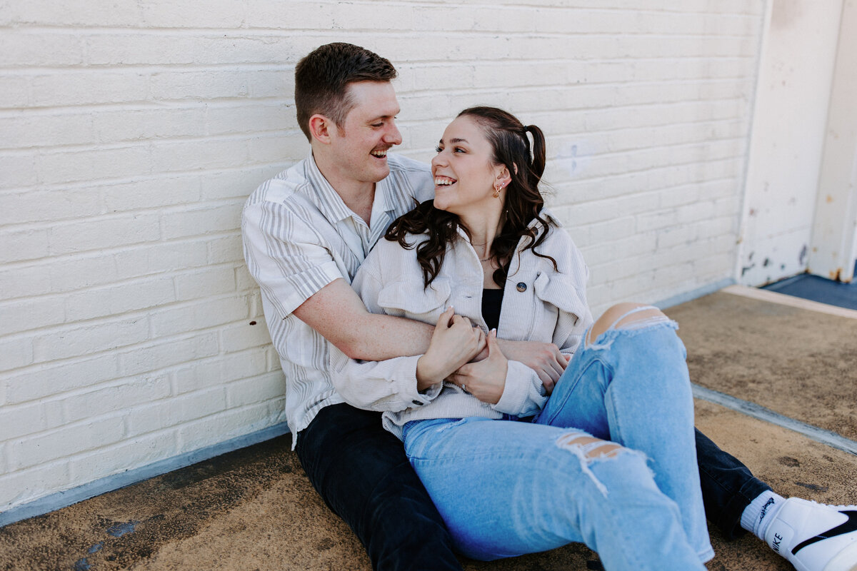 couple sitting on the ground in each other's arms smiling