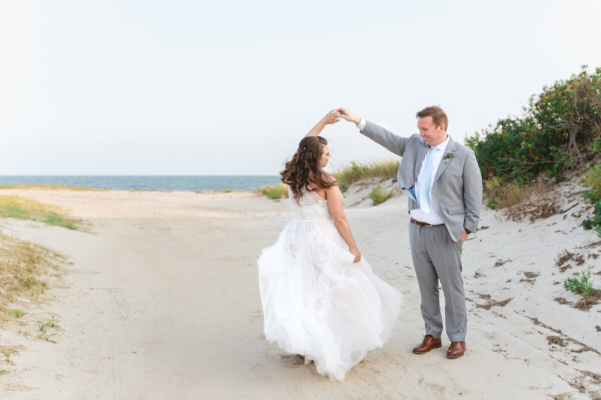 A bride and groom twirl on the beach to celebrate their wedding