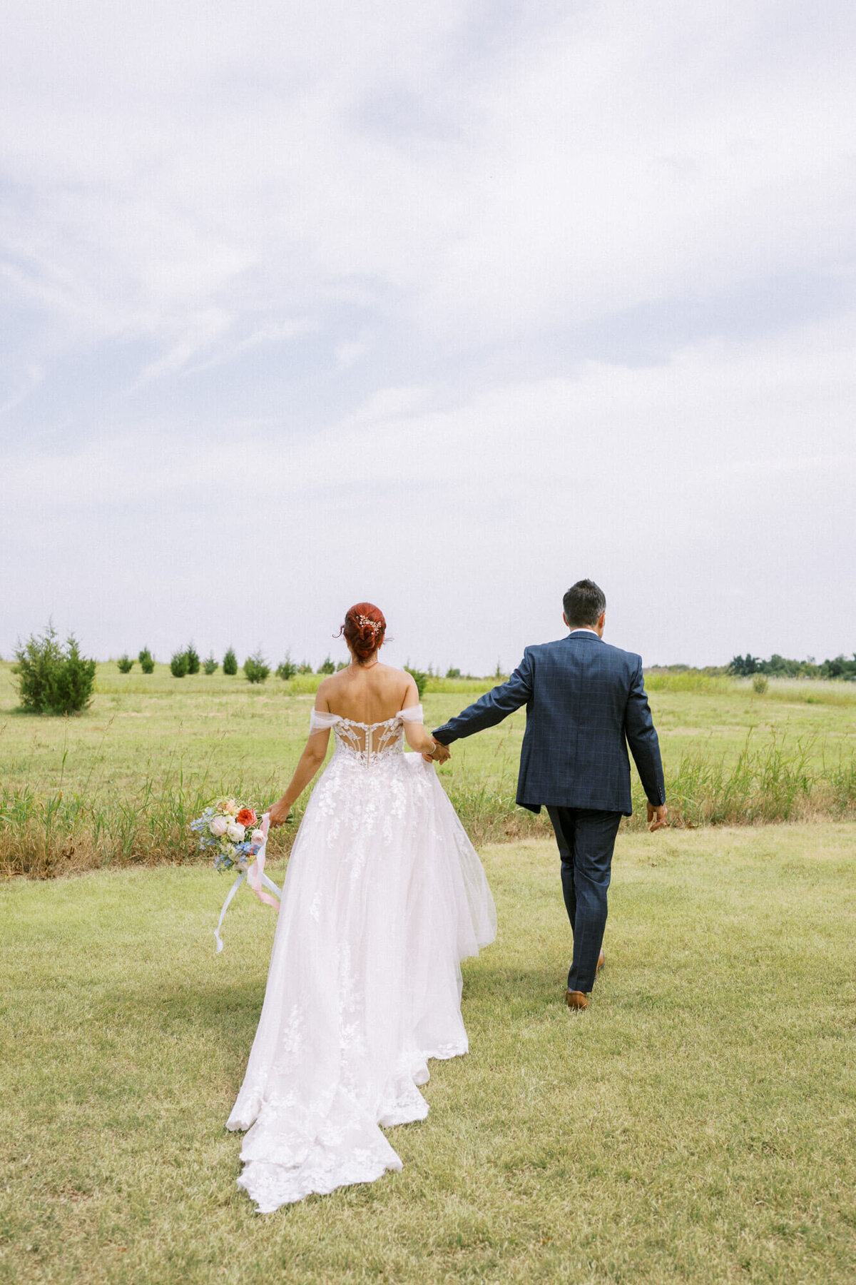 bride-and-groom-walking-through-field