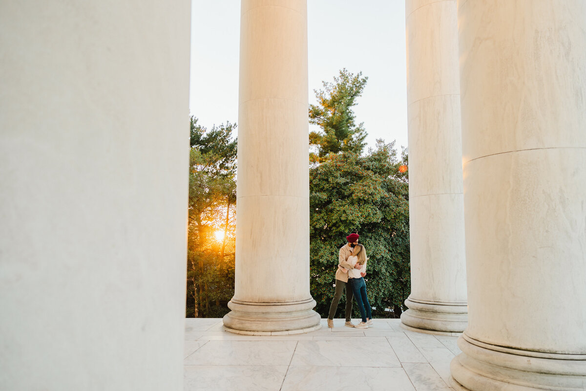 A couple hugs one another surrounded by big columns in Washington DC.