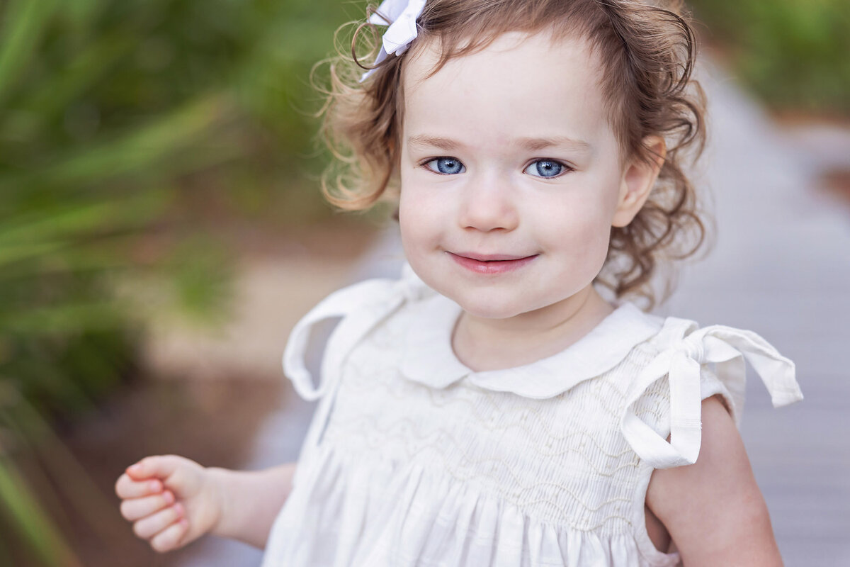 closeup photo of toddler girl with brown hair and blue eyes at Rosemary Beach, Florida.