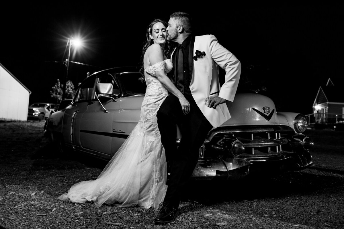 A bride and groom share a moment in front of a classic Cadillac in a break during their wedding reception near Spokane, Washington..