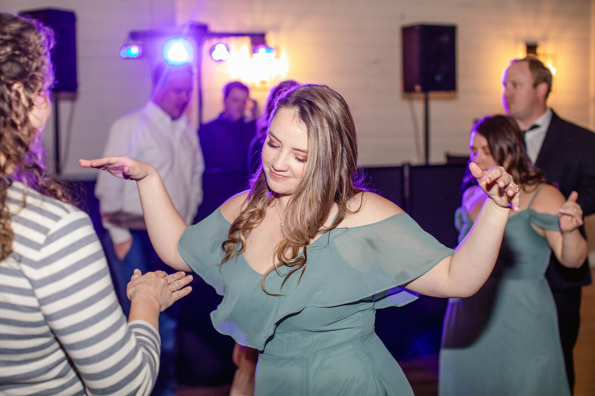 Fort Worth wedding photographer captures bridesmaid in green dress dancing in dj light