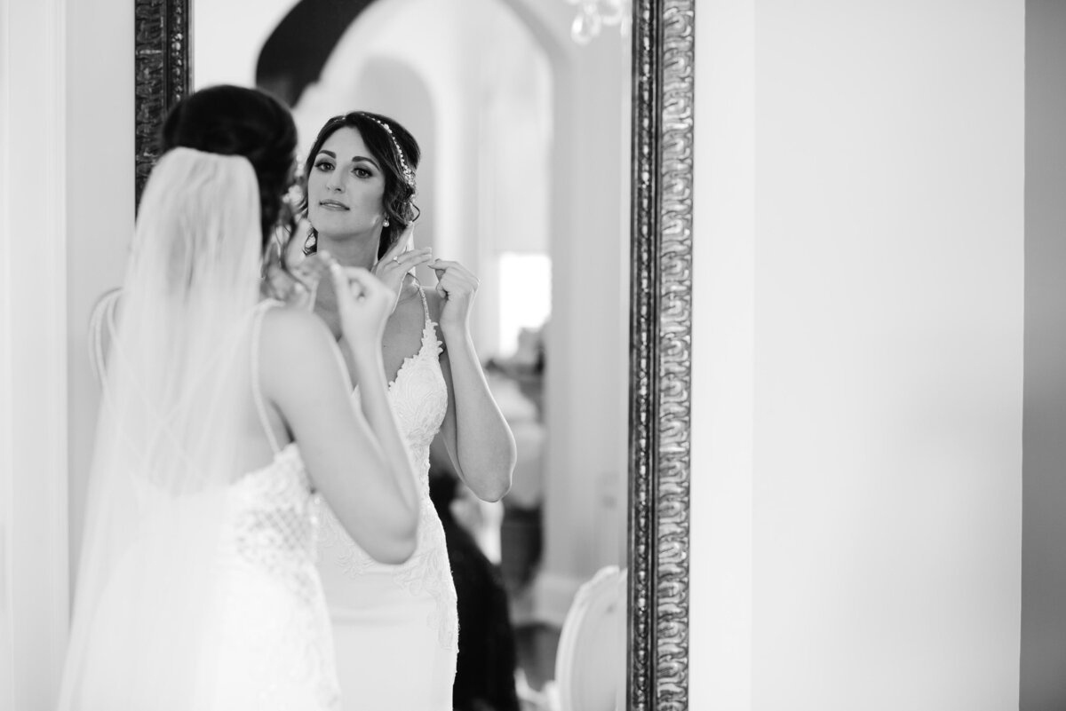Shot by Toronto Wedding Photographer - Bride in her wedding dress putting on jewelry
