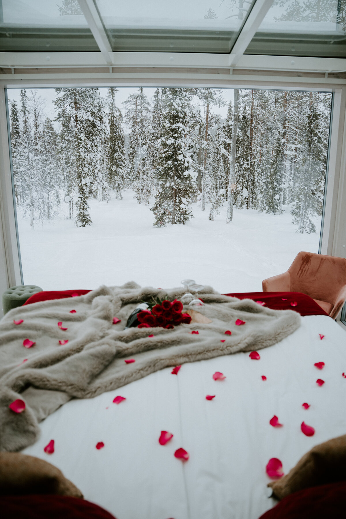 Proposal bed ready with roses, wine, view of the snow in the trees