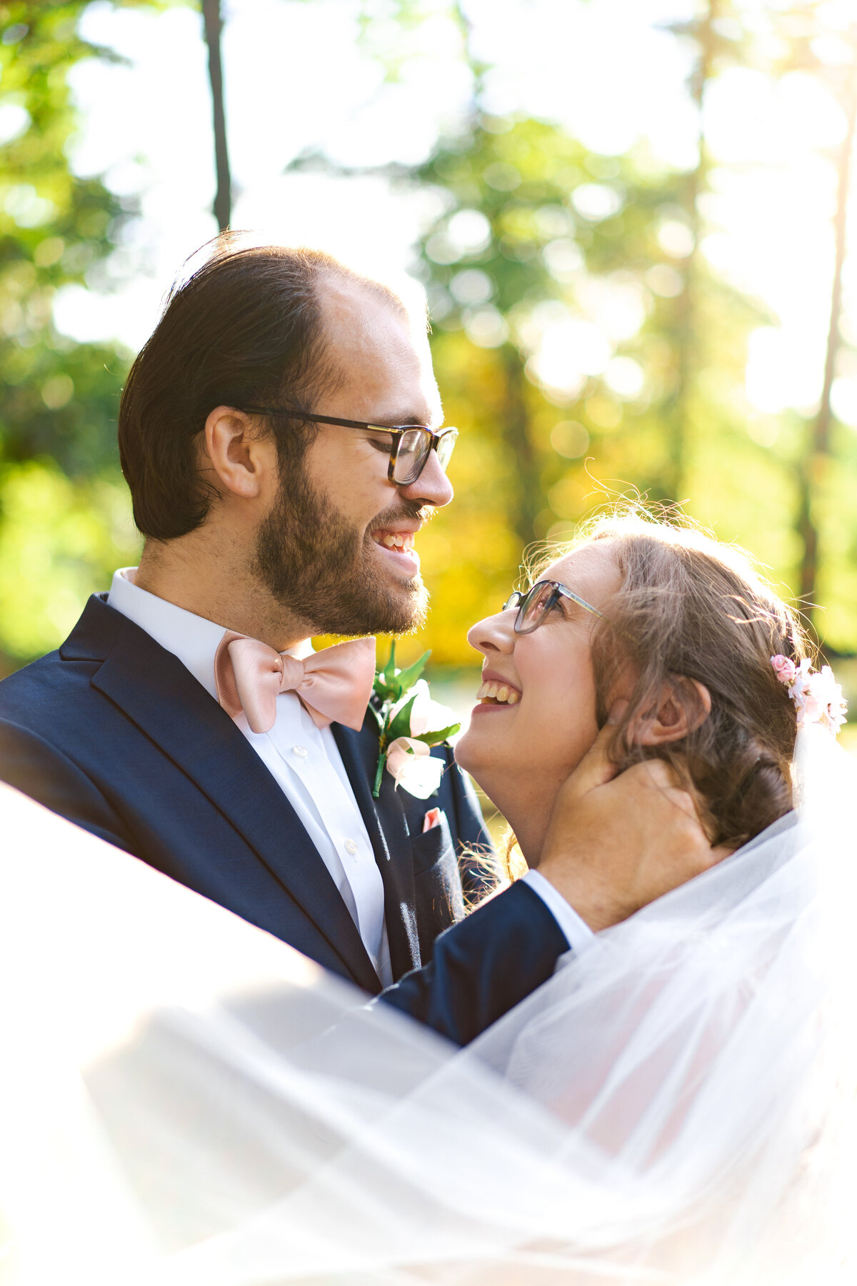 Bride and groom look cheerfully at each other with the veil leading toward the camera at their wedding the Akron Woman's City Club.