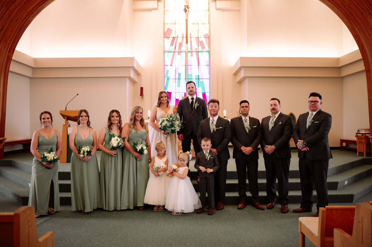 wedding party standing at the alter of the church