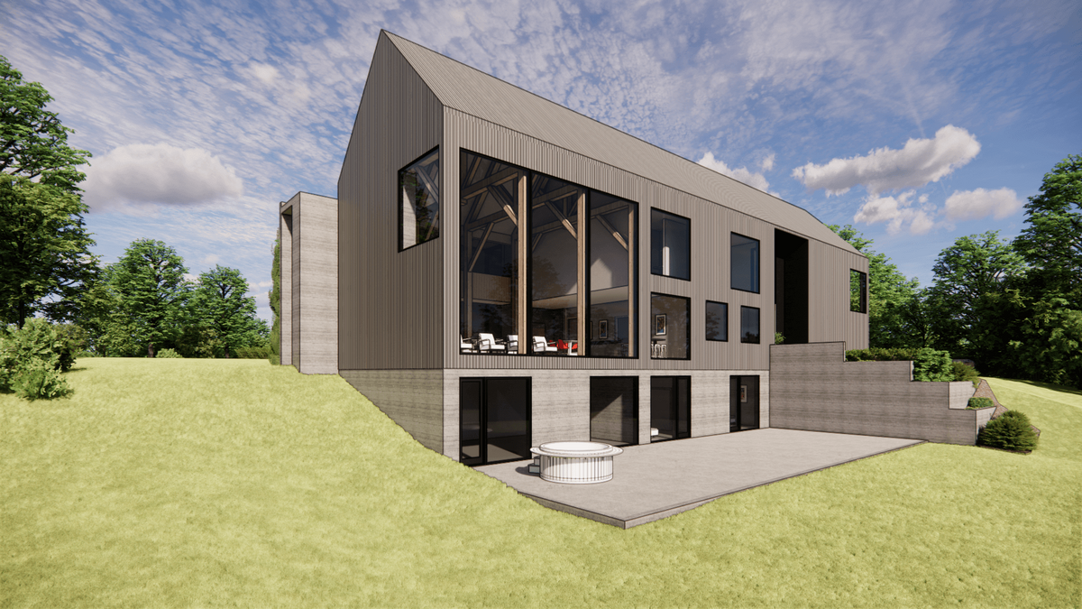 Modern, two-story house with large windows and a sloped roof, set on a grassy hillside. The house features a patio with a circular outdoor hot tub. Surrounding the home are lush green trees under a partly cloudy sky.