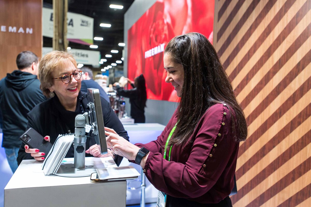 Two female Freeman sales representatives work at the Freeman booth selling their services