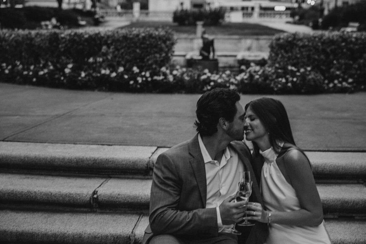 A couple leaning in to kiss while sitting on a staircase 