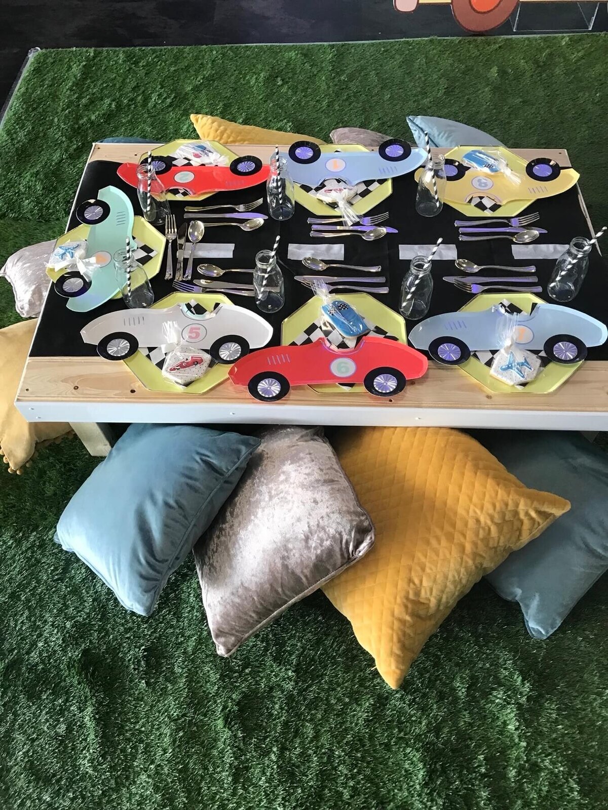 Kid's race car party table set up with race car plates and cushions