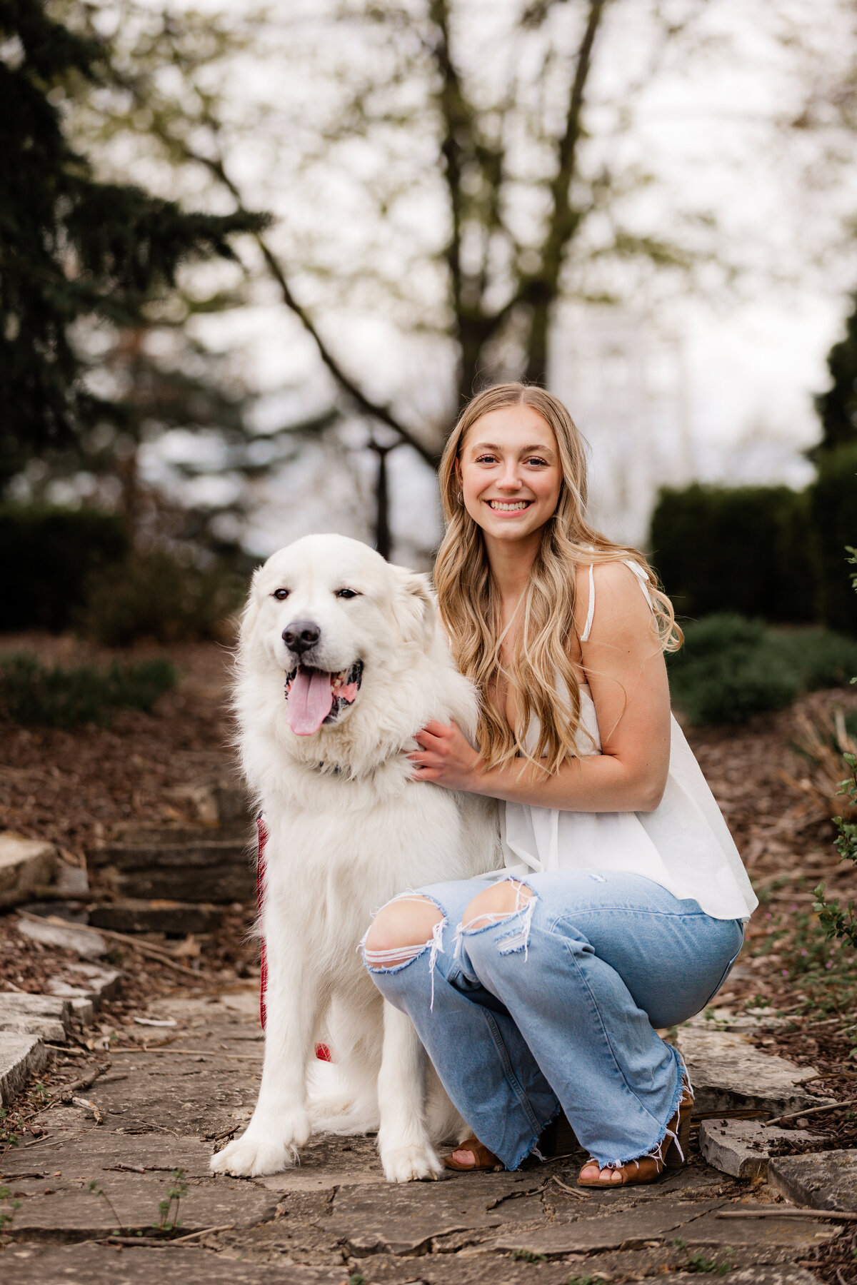 A blonde girl poses with her white dog.