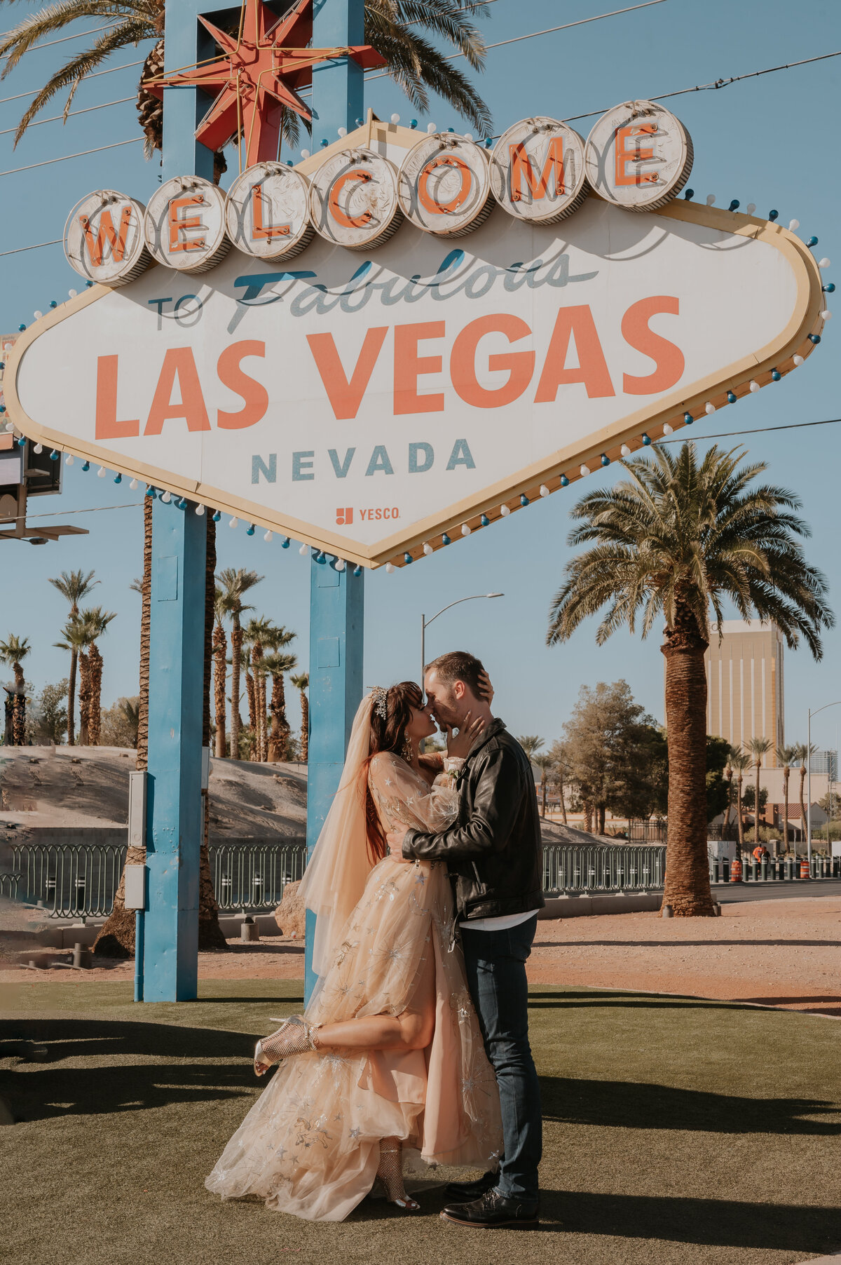 a couple kisses in front of the famous welcome to las vegas sign