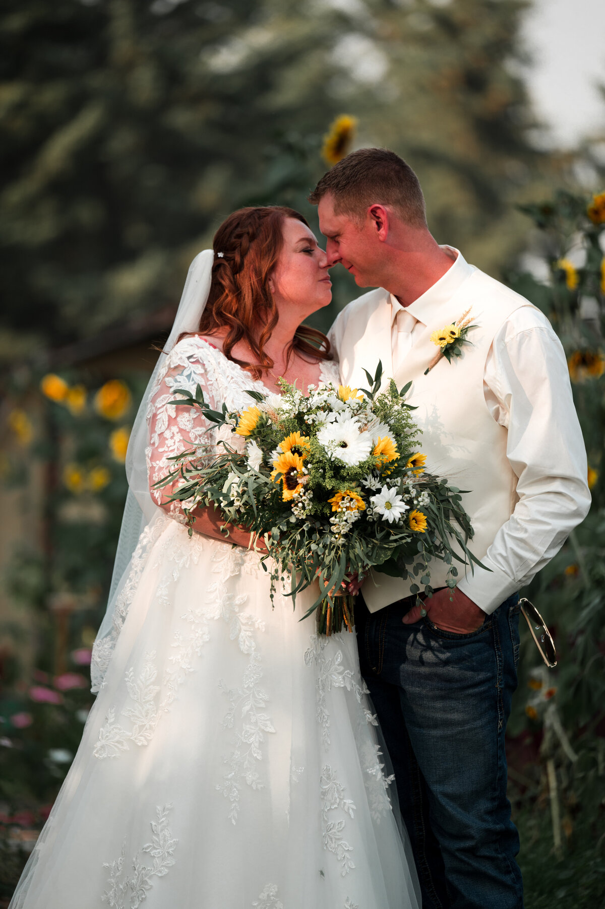 Bride and groom kiss, bride is holding a boquet full of sunflowers
