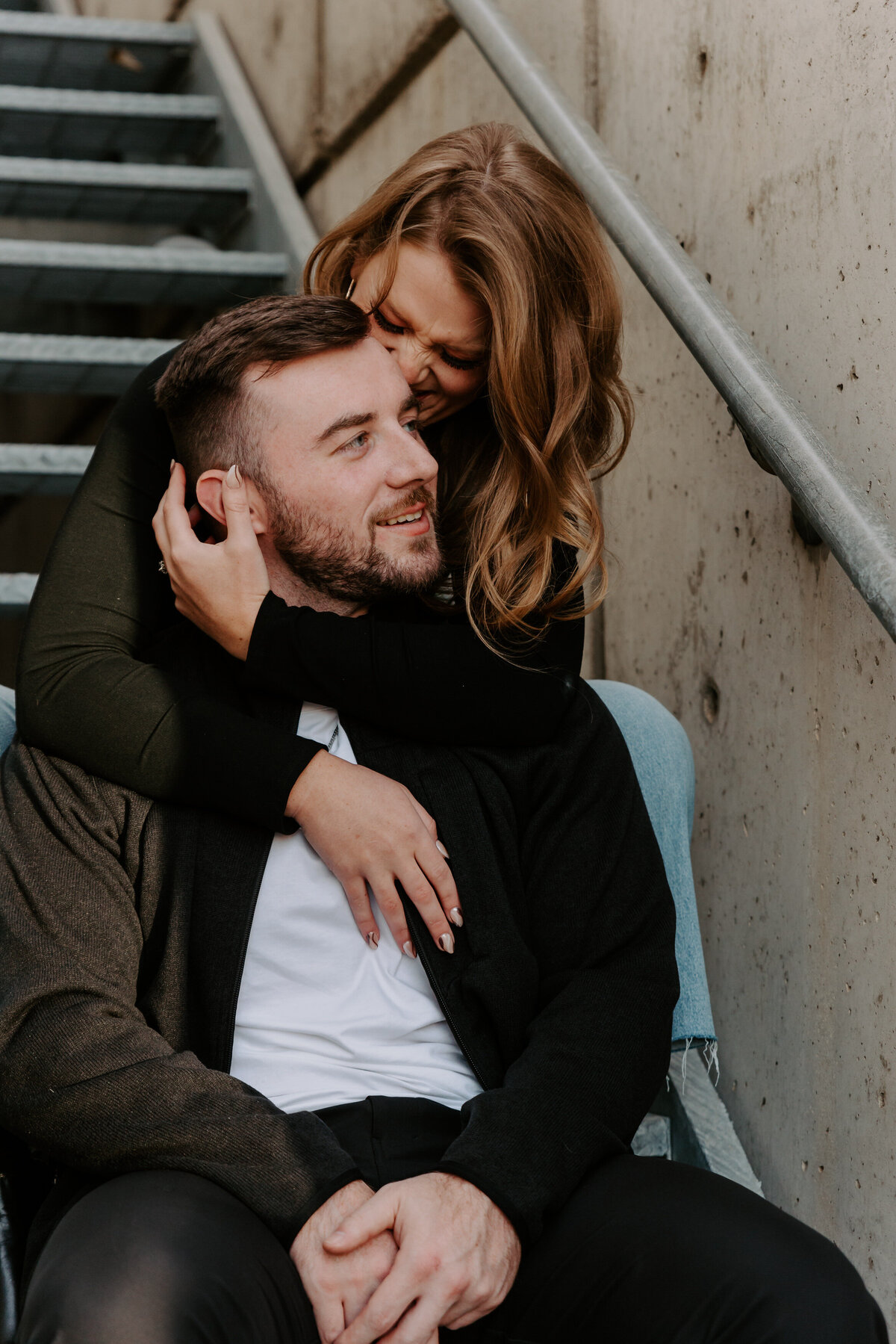 A couple sitting on a staircase as one wraps their arms around the other