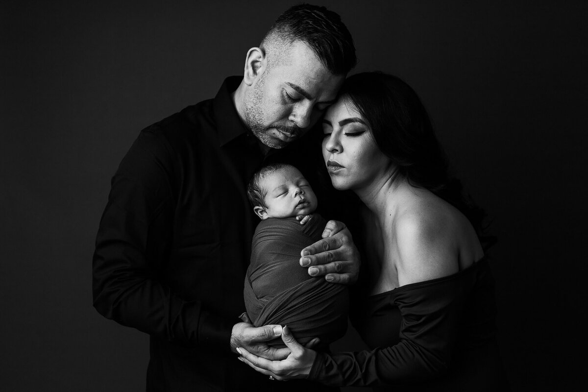 black and white image of baby swaddled with parents