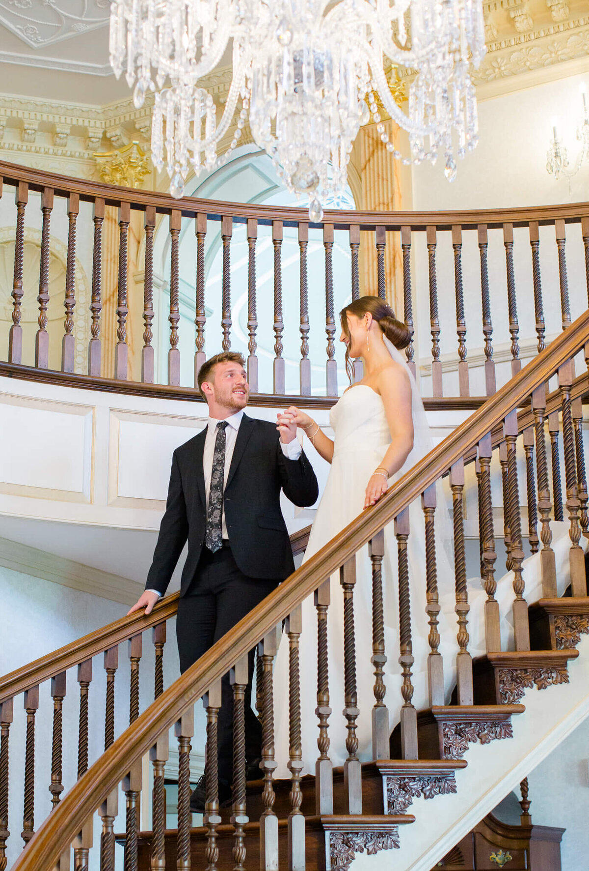 Bride and Groom walking down the stairs in the foyer at The Estate at River Run in Maidens, Virginia. Captured by Charlottesville Wedding Photographer Bethany Aubre Photography.