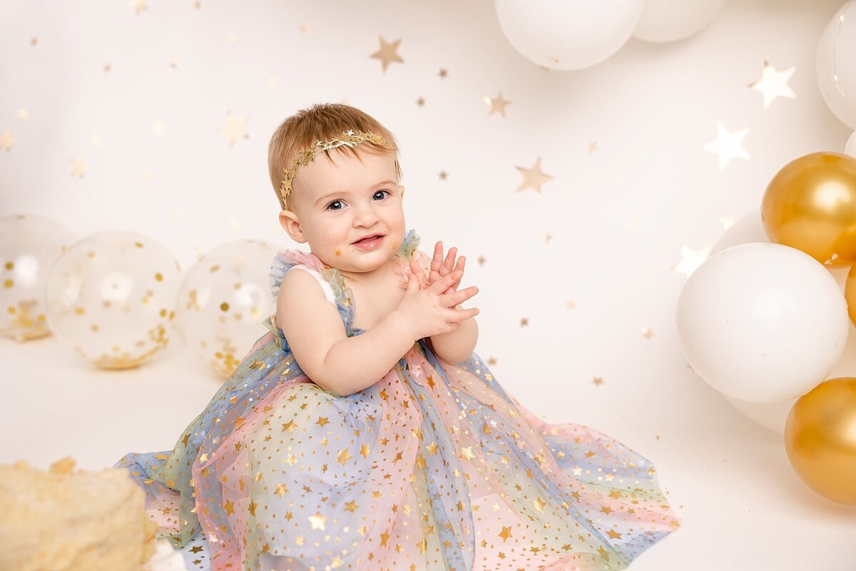 girl in rainbow dress clapping in milestone baby pictures