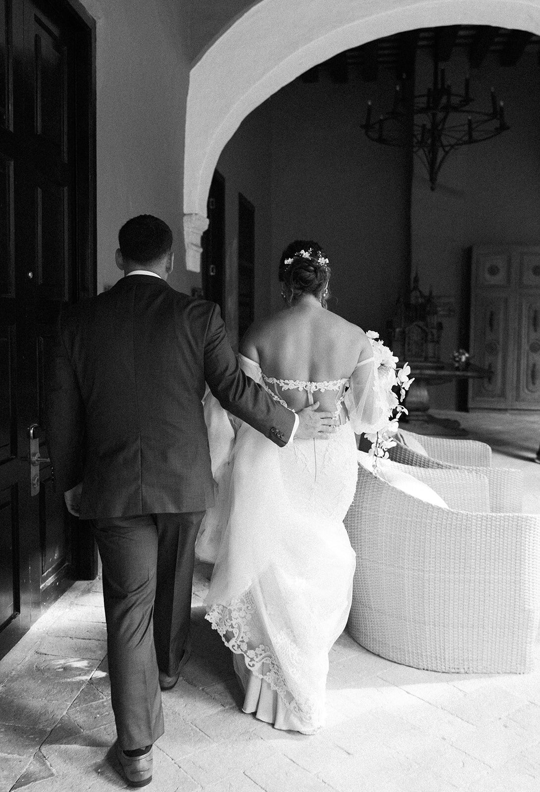 A black-and-white shot of Daniel guiding Victoria into their elegant Cartagena wedding venue.