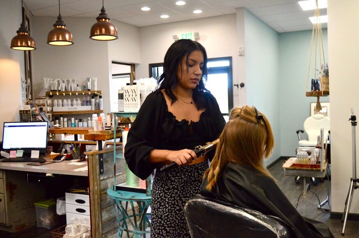 A hairstylist working on a client's hair in a modern salon, showcasing the professional hairstyling services and welcoming environment at 212 Salon, Spa, & Barbershop.