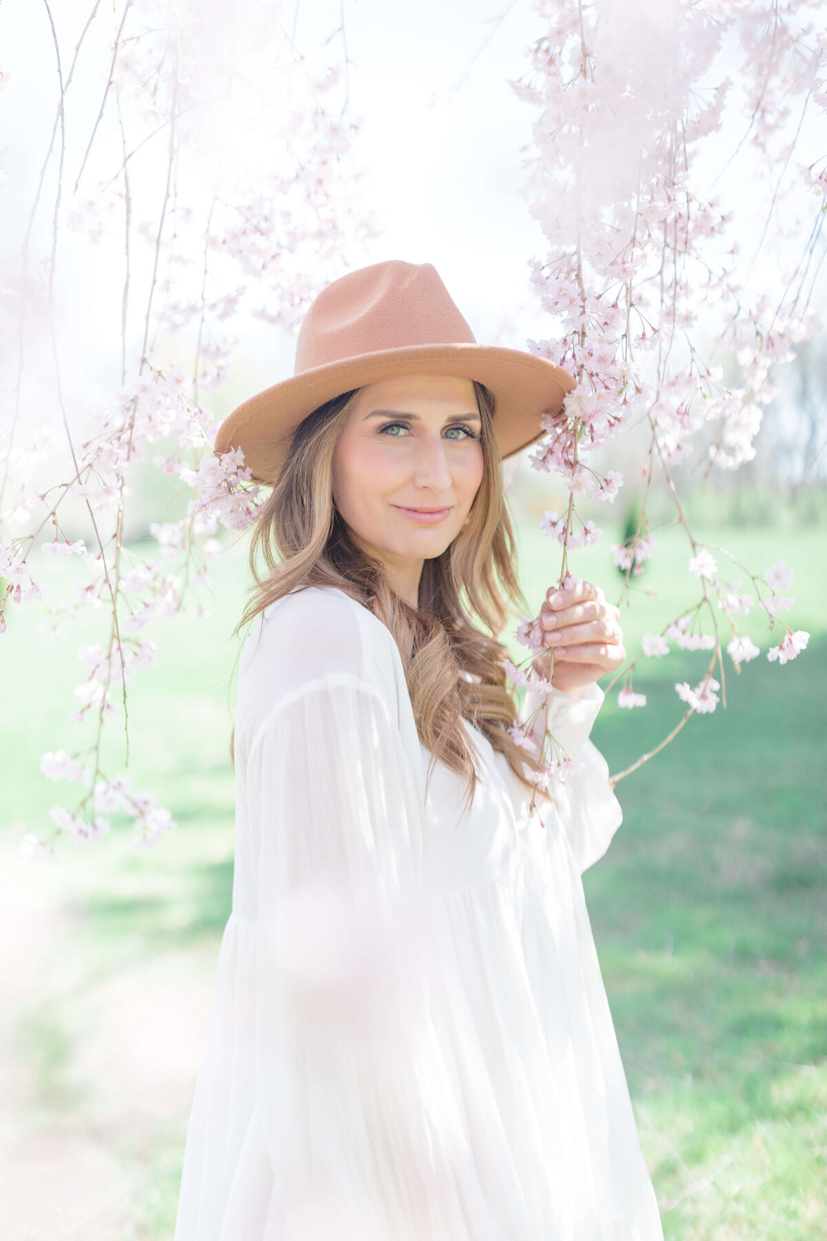 woman in brown hat wearing white dress with cherry blossom