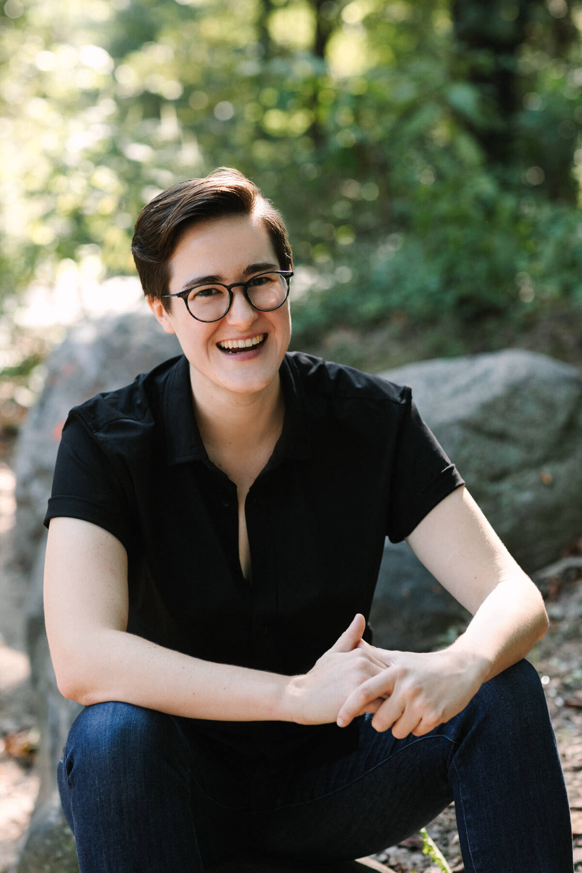 author portrait of camille kellogg sitting on a rock in prospect park