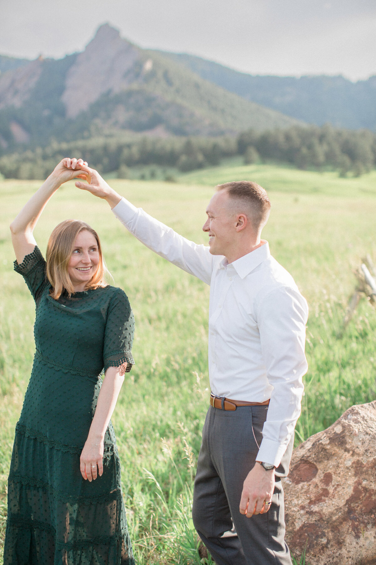 A man twirls his fiancee at Chautauqua Park during their Engagement Photography Session