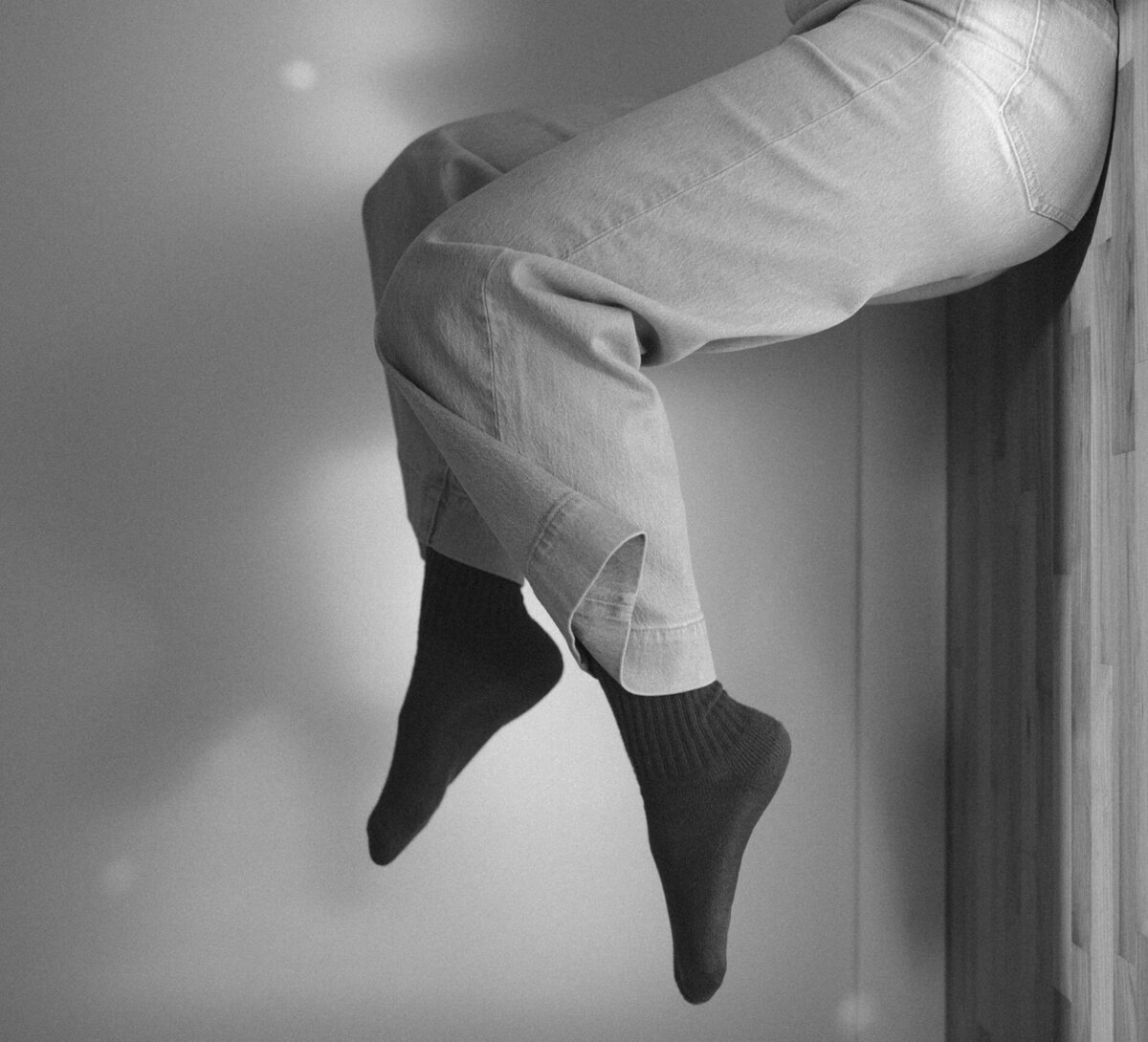 graphic designer poses for a creative photo with her legs and feet against the wall
