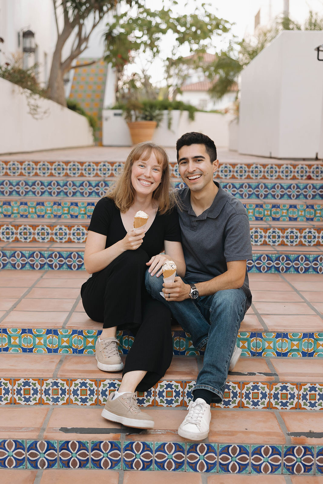 Engaged couple in coordinating outfits sitting on tiled steps