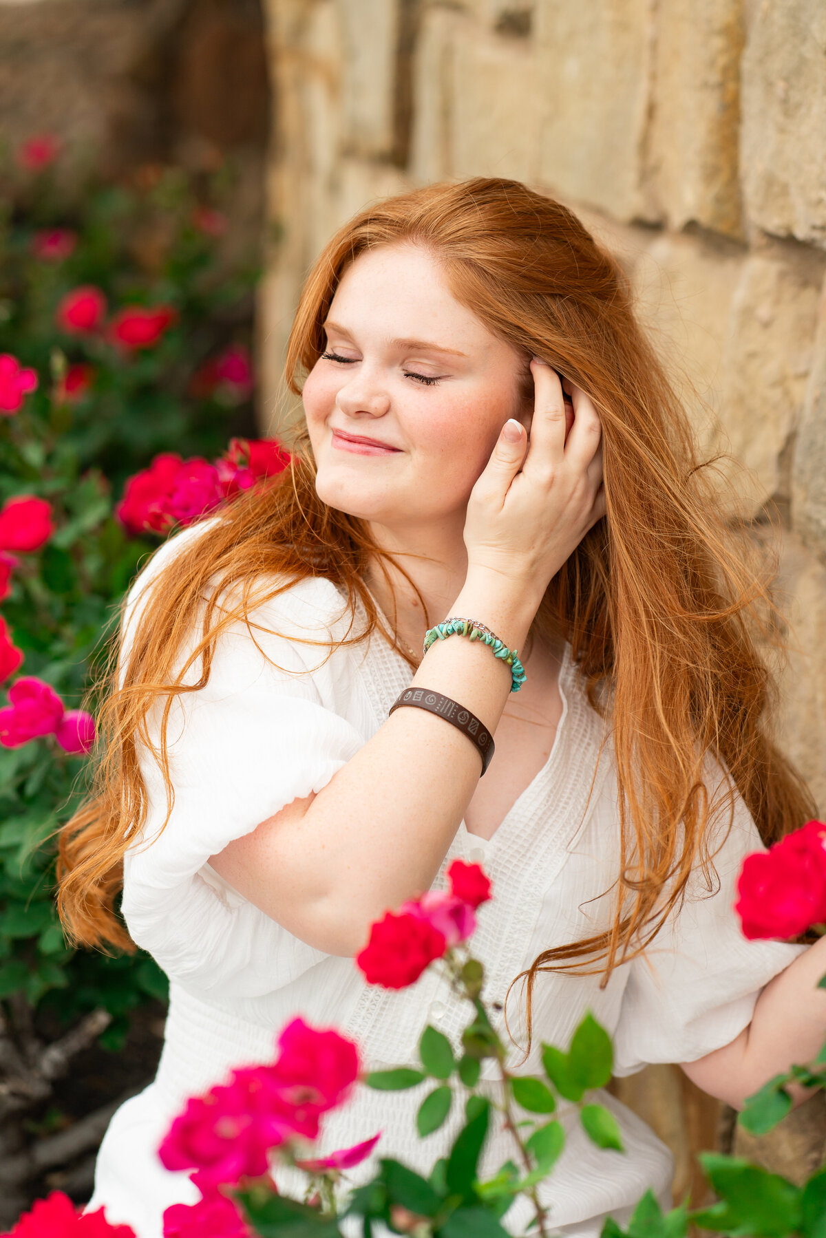 Red head high school senior girl posing in flowers for graduation photos. Austin Senior Graduation.