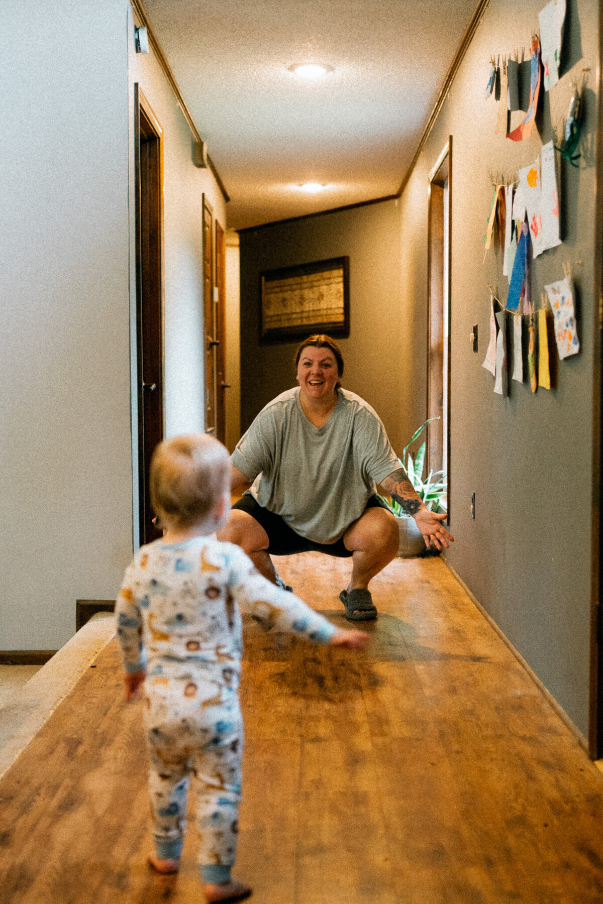 in home documentary photo of a toddler-aged son running towards his open-armed mother.