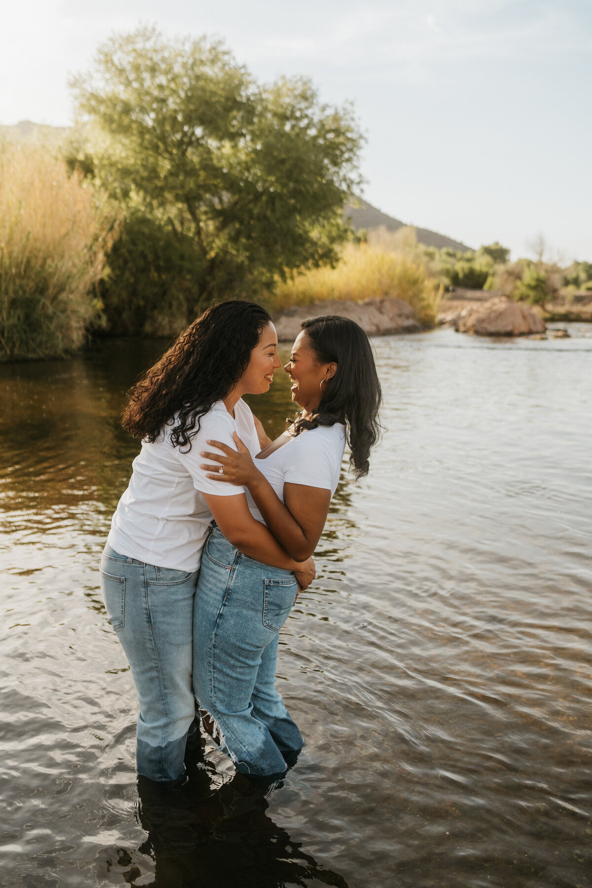 A couple standing in the shallow water of a lake with their arms around each other about to kiss 