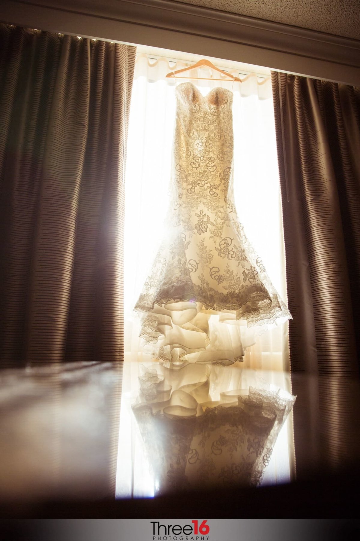 Bride's beautiful wedding dress hangs from the valance