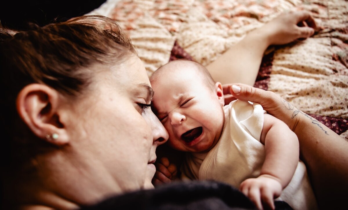 a newborn baby girl crying out next to her mom