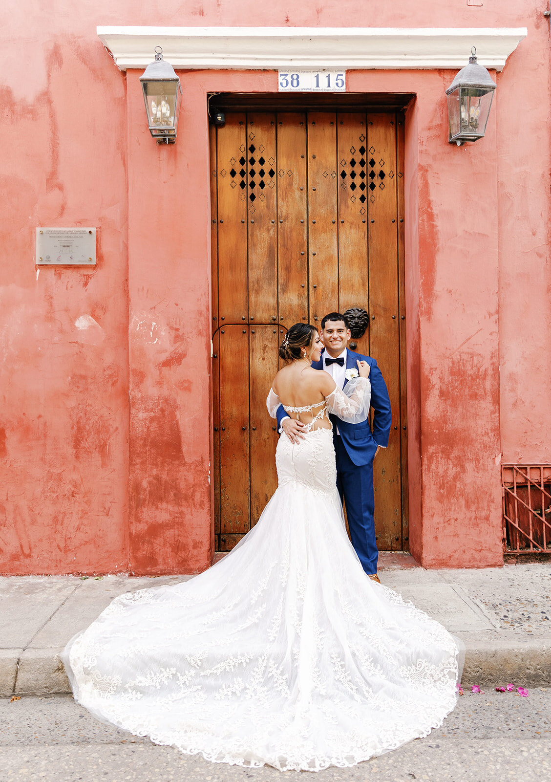 A romantic wedding portrait of Victoria and Daniel sharing an intimate moment against a warm red wall in Cartagena Colombia.